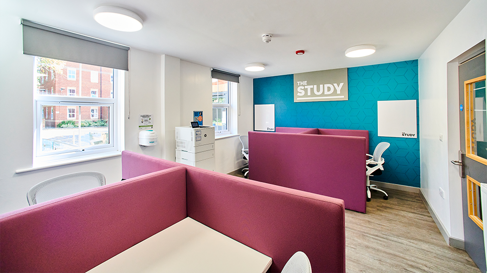 A room with study desks with partitions and a printer