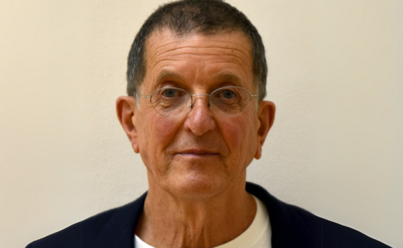 Antony Gormley facing the camera with a plain cream background behind him