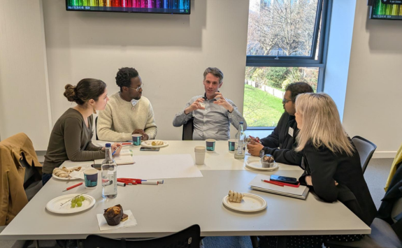 5 people sat round a table in deep discussion