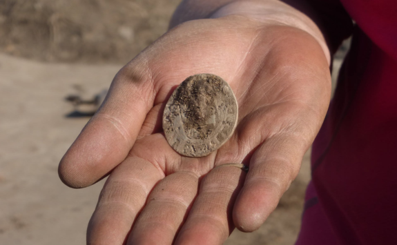 A small coin held in the palm of a bare hand