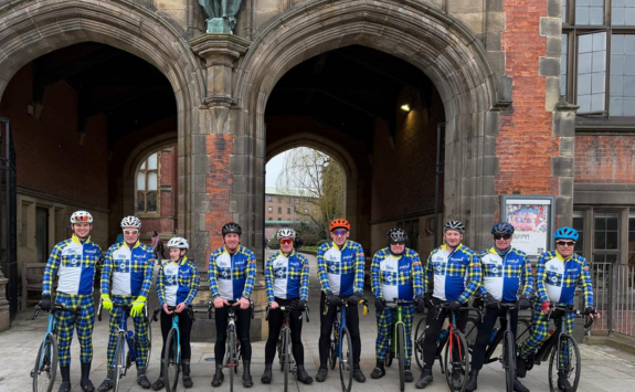 Fergus and fellow cyclists standing in front of the Arches on campus