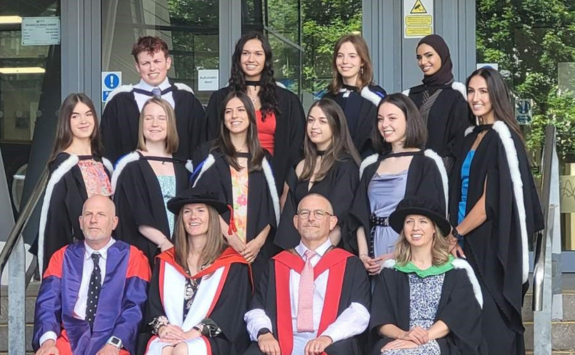 Maria posing outside Medical School with fellow graduates