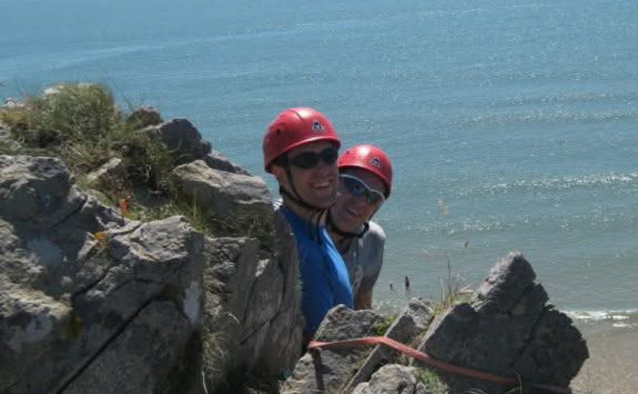 Tim and a friend rockclimbing on a cliff top overlooking the sea