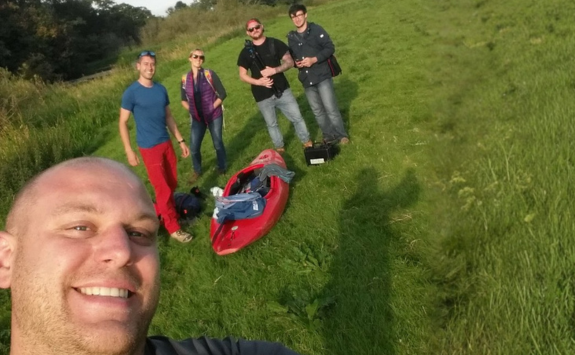 Tim taking a selfie with friends with a red canoe in the background.