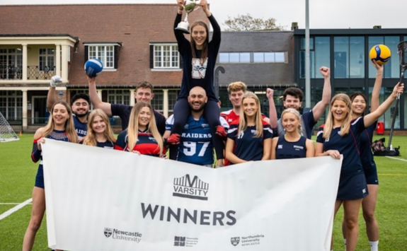 Team Newcastle stand holding a banner proclaiming them Varsity Winners