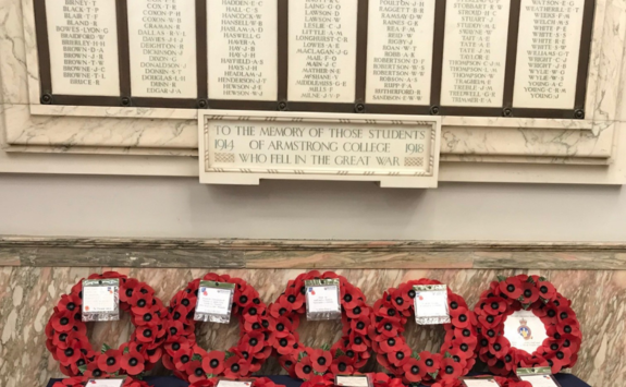 War memorial plaque in Armstrong Building with poppy wreaths laid in front