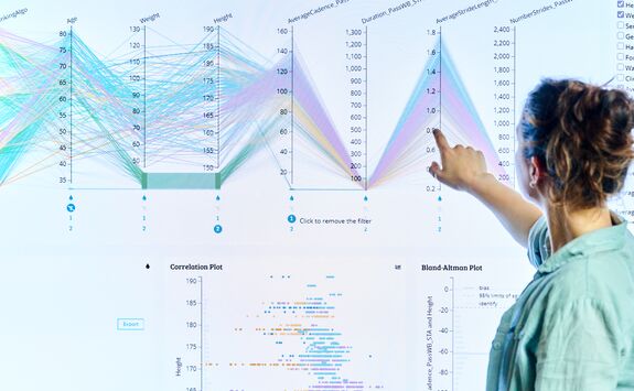 A student is analysing data on a large touchscreen. She is looking away from the camera and reaching out to tough a data point in a graph.