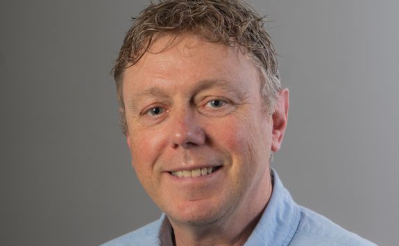 Rick McCordall, the Head of Venture Creation at Newcastle University. Rick is a white male. He has short, blonde, curly hair and blue eyes. He is wearing a light blue shirt. It is a professional headshot with a grey background.
