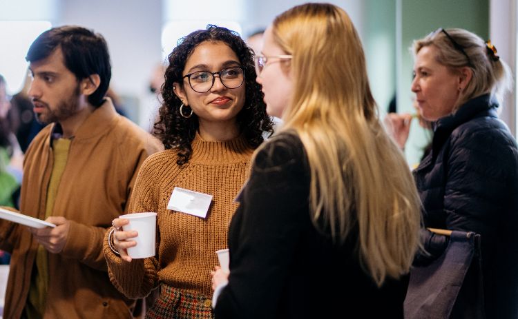Alumni and guests chat during a Newcastle University Business School networking event, with refreshments in hand.