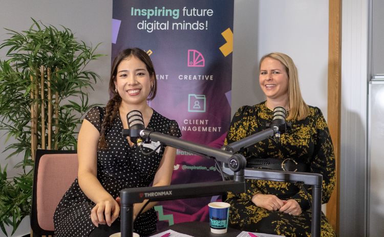 Two women sit in front of microphones during a podcast-style session at the Aspiration Digital 2025 event, with an “Inspiring future digital minds” banner behind them.