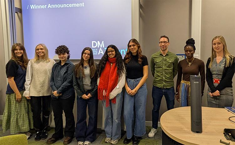 Students and staff stand together at the front of a lecture room following the DMA Creative Lab winner announcement.