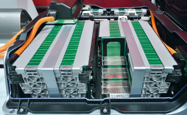 Close-up of an electric vehicle battery pack showing rows of battery cells and electrical cables.