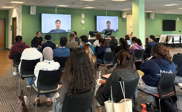 Group of MBA students seated in St James’ View at Newcastle University Business School, attending a careers session with a guest speaker joining via video conference.