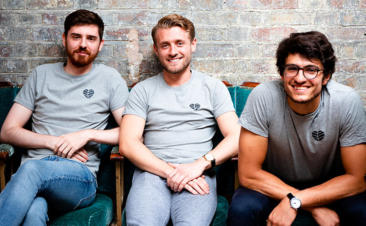 The three graduates who run Planty sit on chairs and smile at the camera