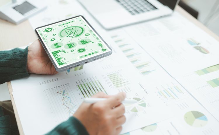 Person reviewing sustainability data on a smartphone alongside printed charts and reports.