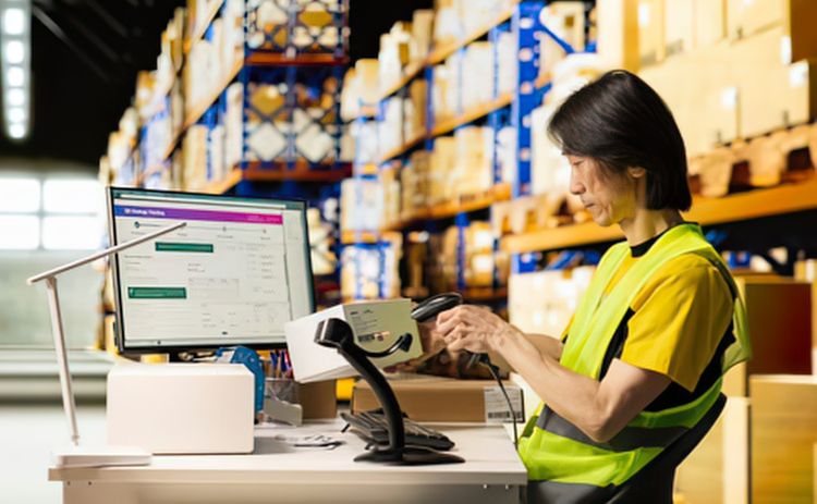Warehouse worker scanning a package with a handheld barcode scanner.