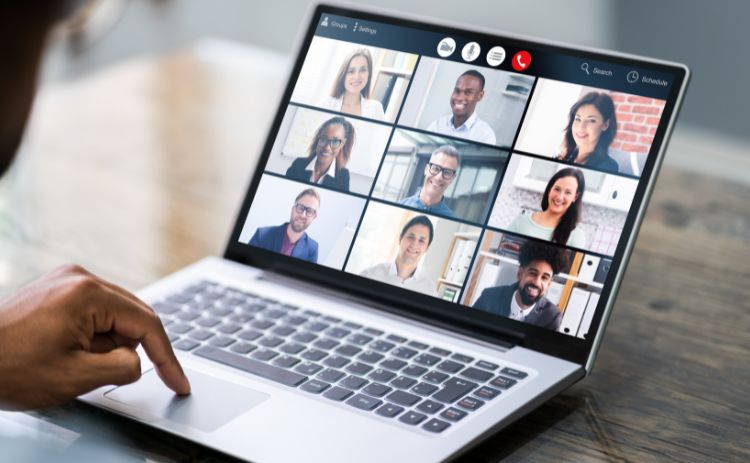 Online alumni webinar with participants joining a video call from different locations, displayed on a laptop screen.