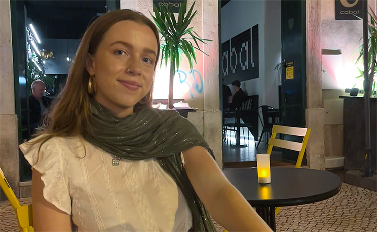 Wendy Mcloughlin sat at a table in a cafe, with tables and ambient lighting in the background.