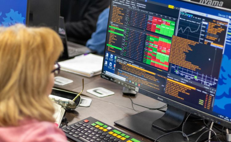 A blonde woman analysing live global market data on Bloomberg Terminal screens in a university trading lab