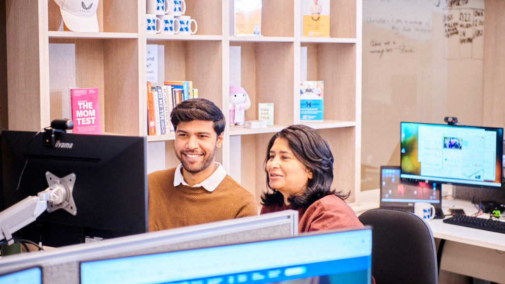 A male and female student sit together looking at the same computer screen in collaboration