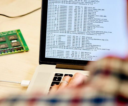 A researcher working at laptop with a piece of computer hardware connected to his laptop.