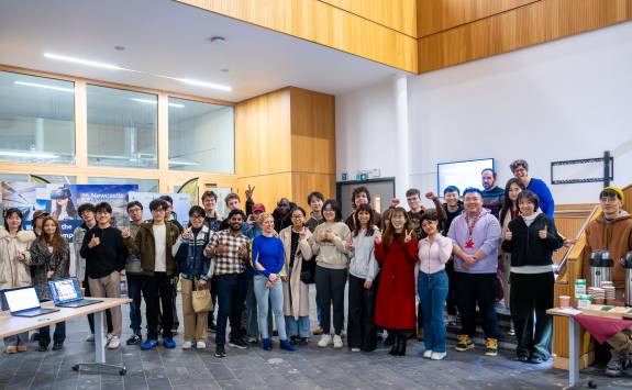 A group of approximately 30 students and staff smile at the camera