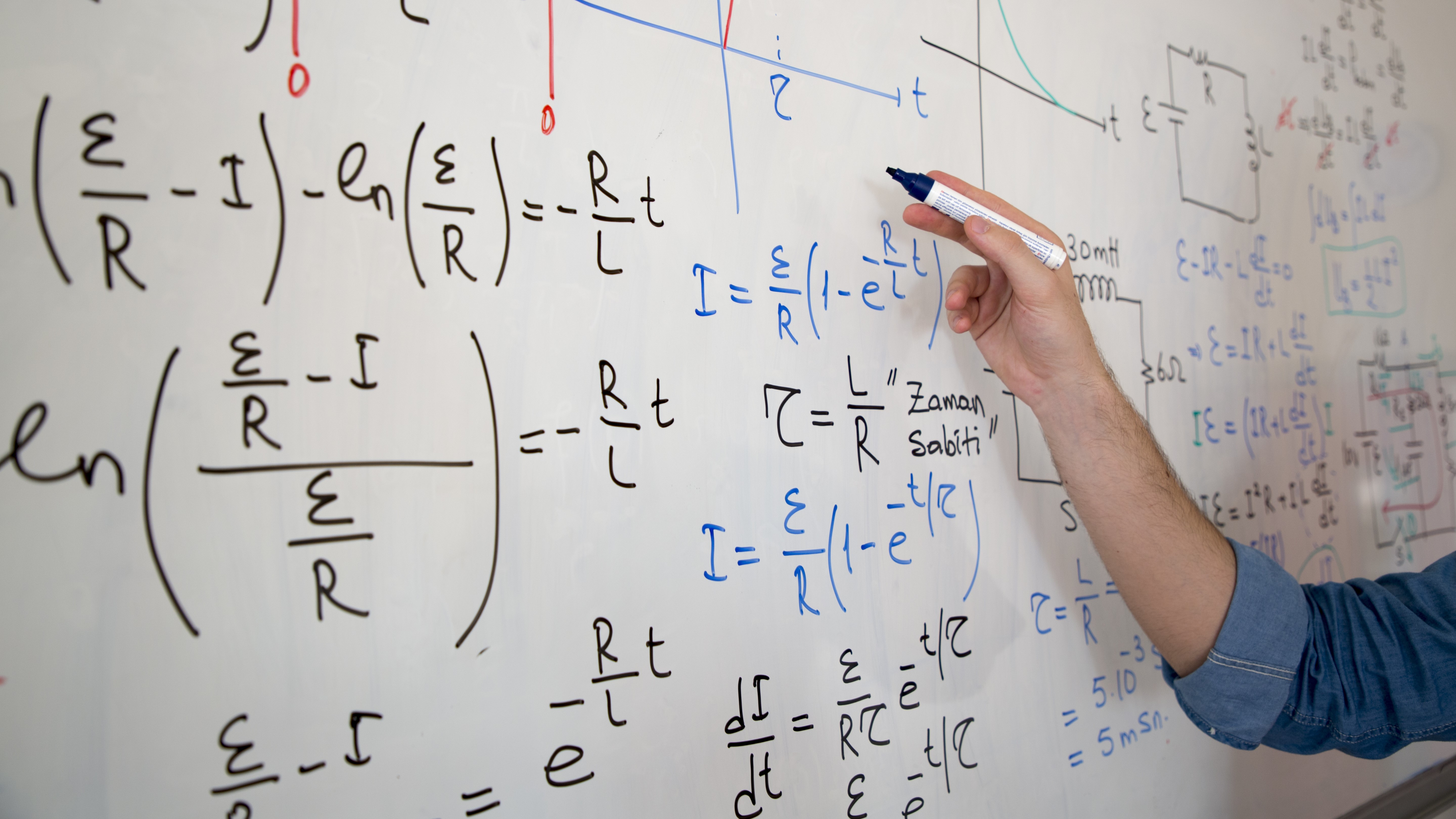 A hand writing mathematical equations on a whiteboard