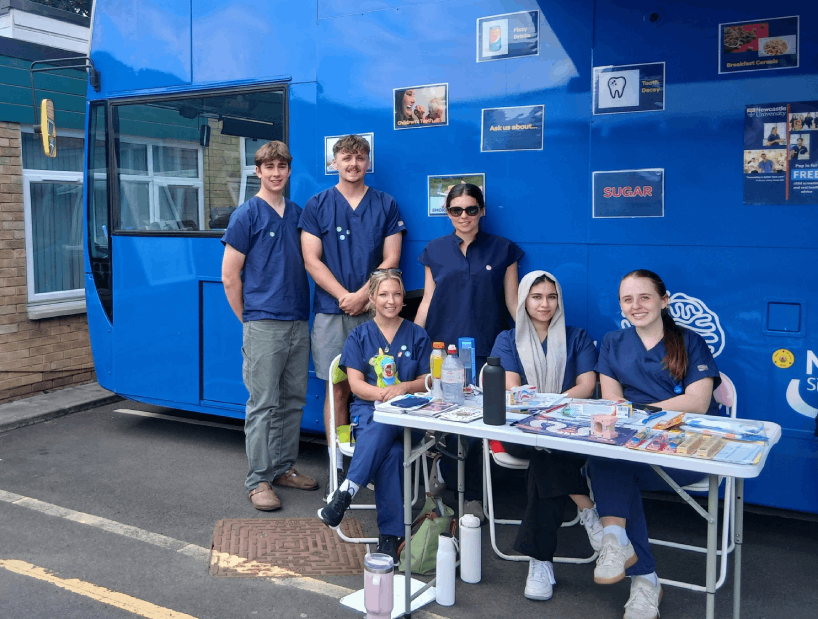 group of students sitting and standing outside the NHS MELISSA Bus