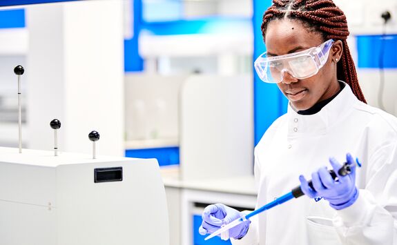 A student wearing goggles and a labcoat working in a chemical engineering lab.
