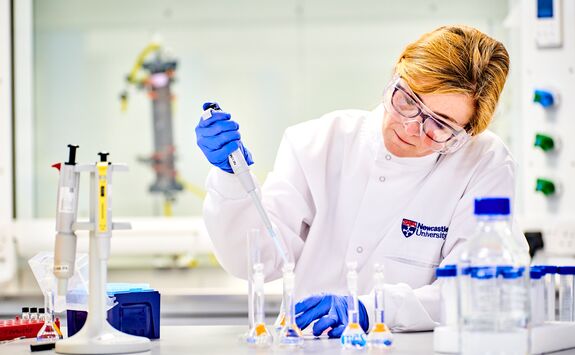 A woman in a labcoat working with chemicals.
