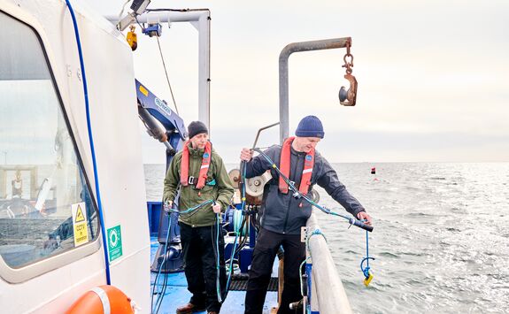 Two researchers working on a boat at sea.
