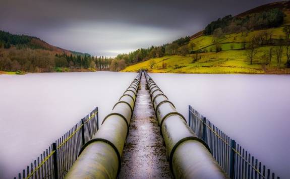 Two above ground water pipes running over a body of water.