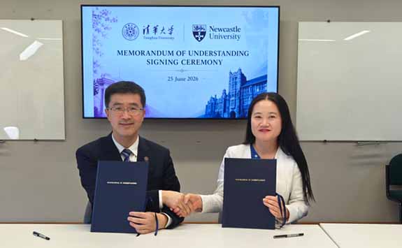 Delegates from Tsinghua University and Newcastle University pose with a partnership agreement indoors.