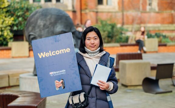 Student holding a welcome sign