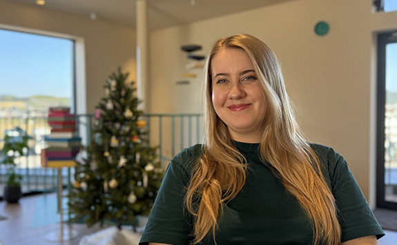 Morgan smiling at the camera with a Christmas tree in the background.