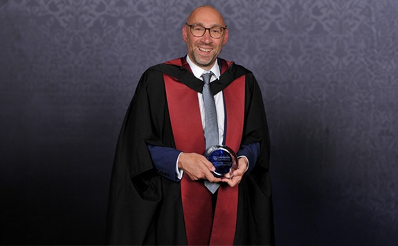 JC Penet in Graduation robes holding VC