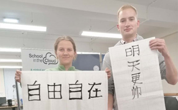 Two students holding up examples of their calligraphy. 