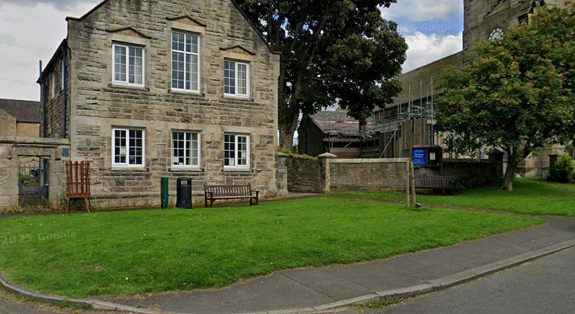 An old stone building with a large patch of grass in front