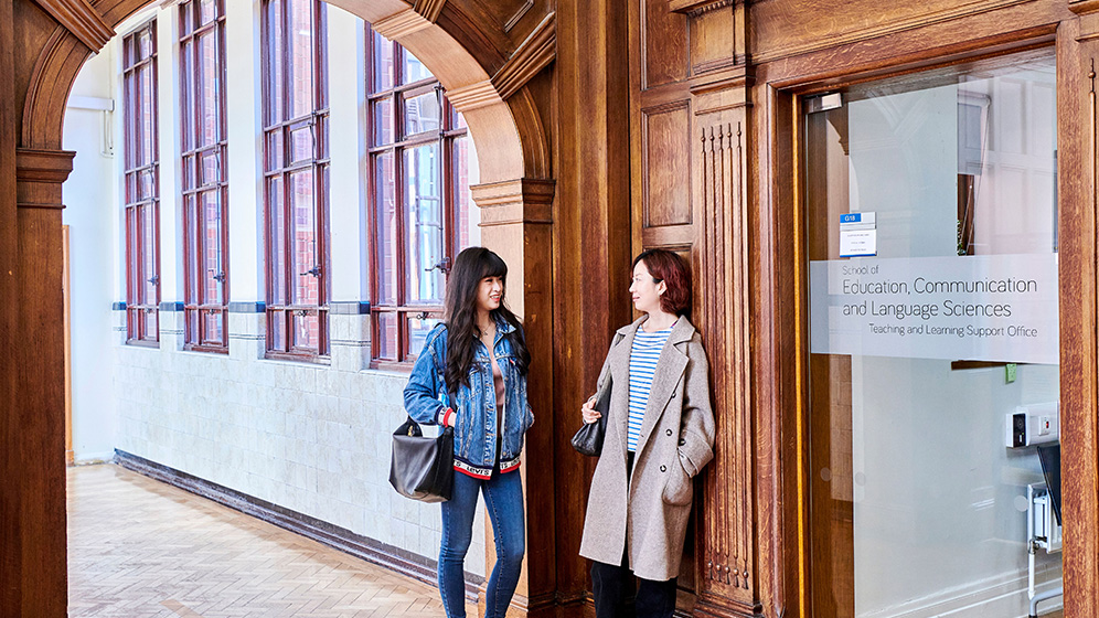 2 students standing chatting in the School corridor