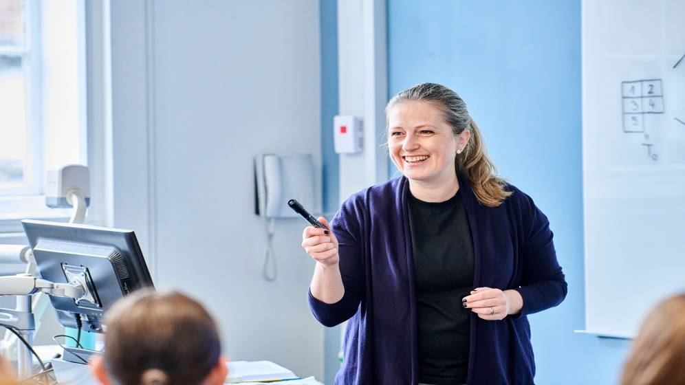 A woman smiling while delivering a presentation.