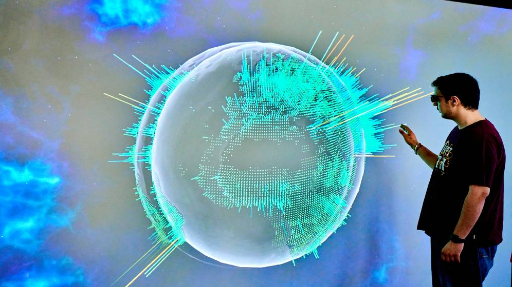 A student looking at a map of the globe on a large interactive whiteboard.