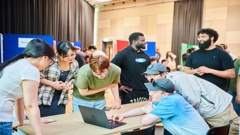 A group of students gathered round a computer at a hackathon.
