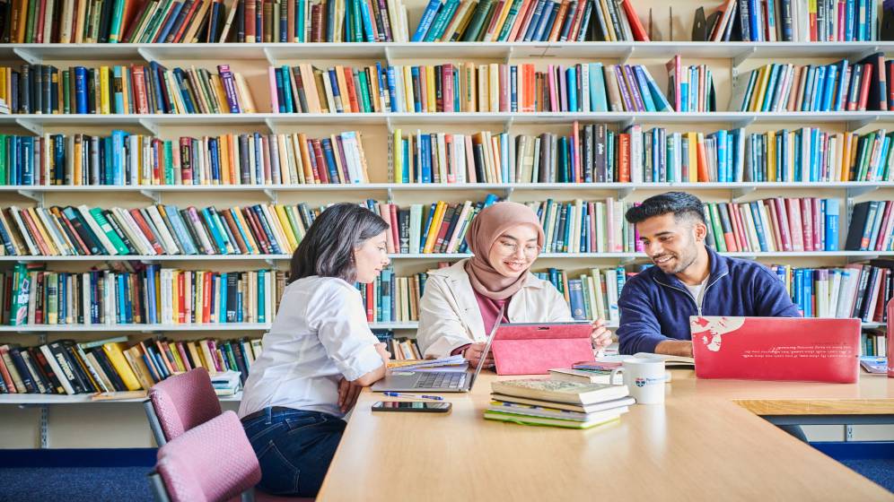 Three students working in a library.
