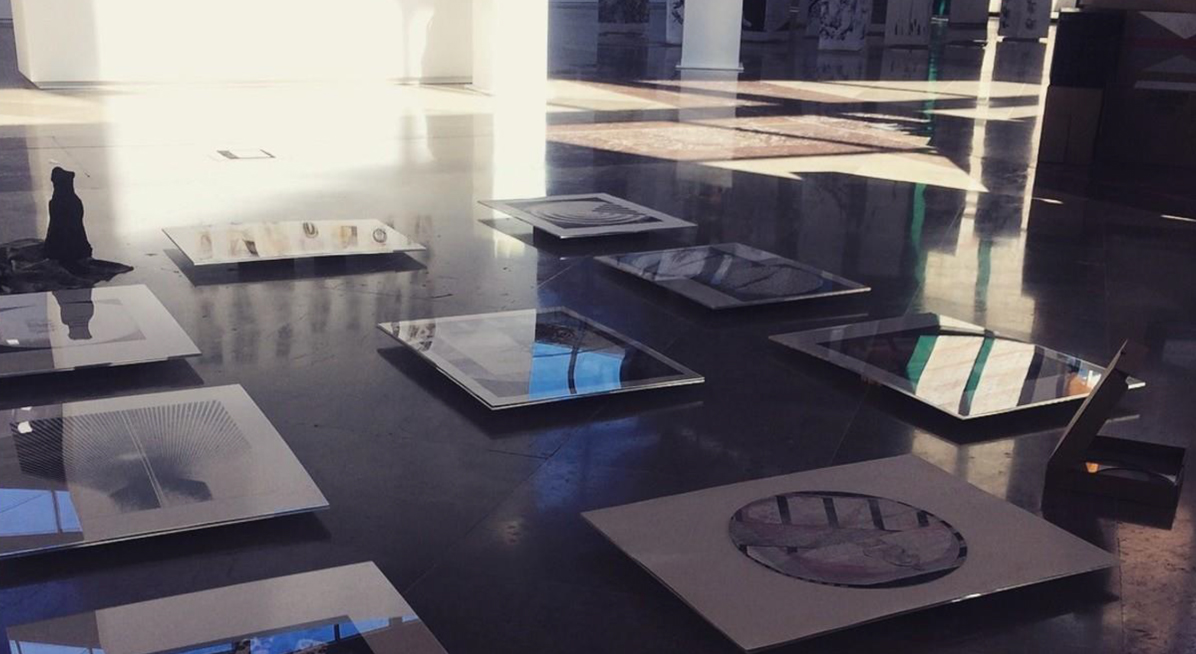 Exhibition with a series of large prints displayed on the floor