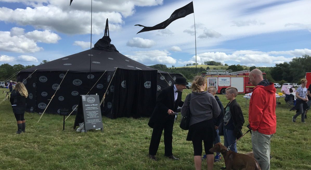 marquee in field. Man talks to a family
