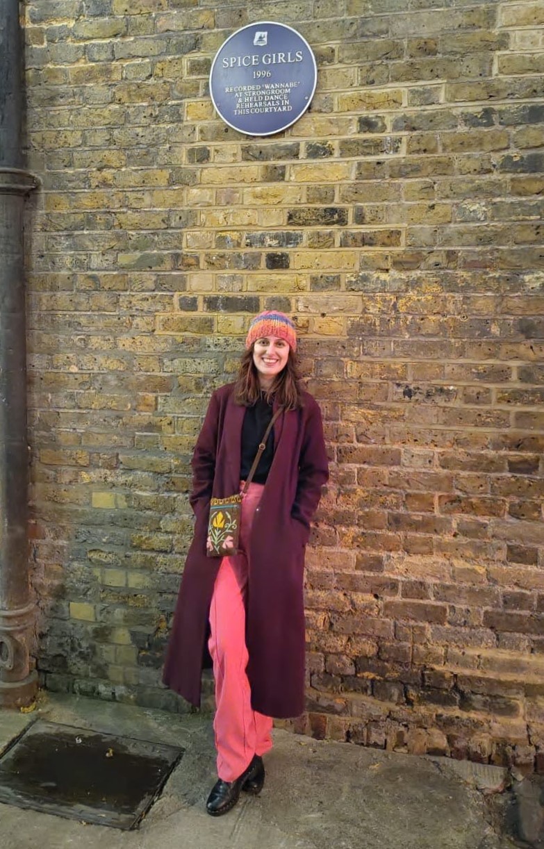 Isabel Thomas standing in front of a blue plaque that says Spice Girls