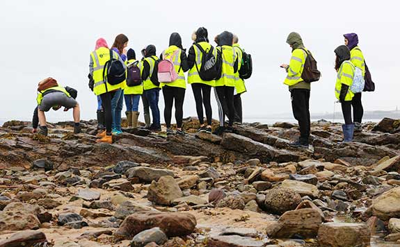 students in high viz stand in a group on a fieldtrip