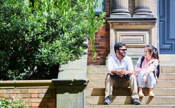 Two students sitting outside in the sunshine.