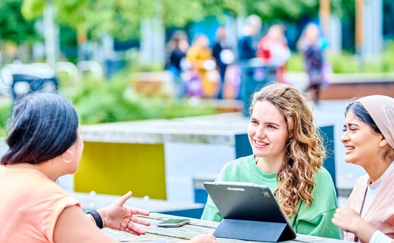 Three students sat outside at the Helix site.