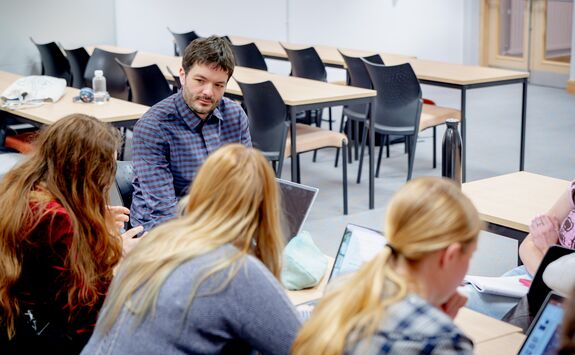 A staff member listens to a group of students.